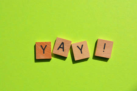 Yay! exclamation in wooden alphabet letters isolated on bright green background