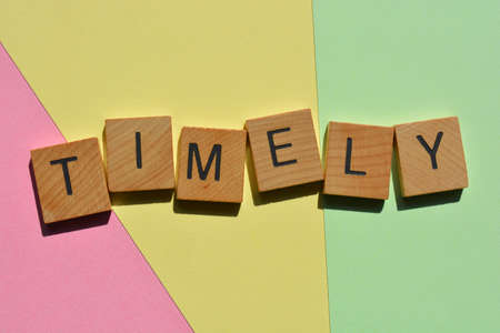 Timely, word in wooden alphabet letters isolated on colourful background as banner headline