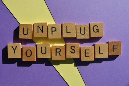 Unplug Yourself, words in wooden alphabet letters isolated on purple and yellow backgroundの写真素材