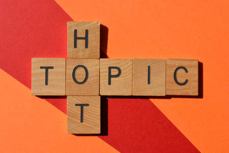 Hot Topic, words in wooden alphabet letters isolated on red and orange backgroundの写真素材
