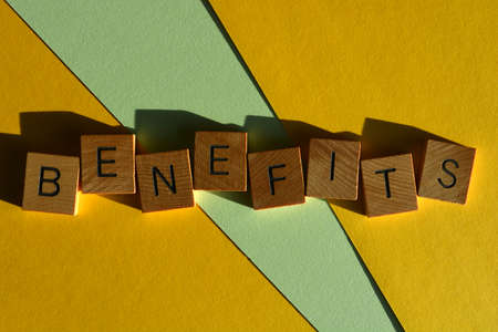 Benefits, word in wooden alphabet letters isolated on yellow and green backgroundの写真素材