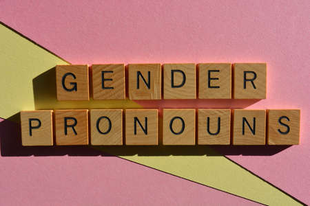 Gender Pronouns, words in wooden alphabet letters isolated on pink and yellow backgroundの写真素材