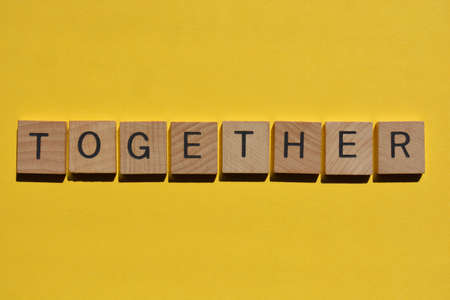 Together, word in wooden alphabet letters isolated on bright yellow backgroundの写真素材