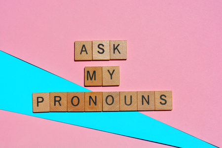 Ask My Pronouns, words in wooden alphabet letters isolated on pink and blue background