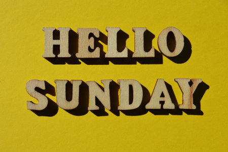Hello Sunday, words in wooden alphabet letters isolated on yellow background