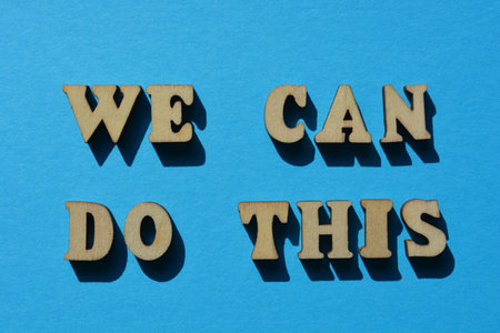 We Can Do This, words in wooden alphabet letters isolated on blue backgroundの写真素材