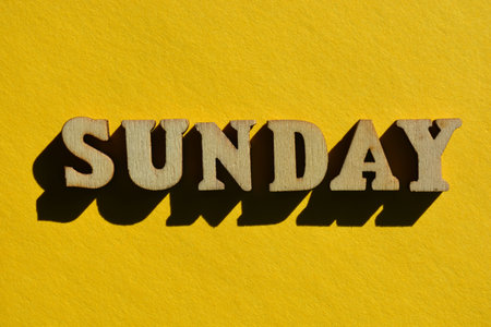 Sunday, word in 3d wooden alphabet letters isolated on yellow background