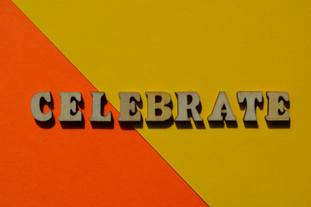 Celebrate, word in wooden alphabet letters isolated on bright yellow and orange backgroundの写真素材