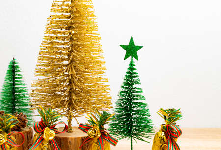 Gold Christmas trees and green Christmas trees with gold bells on the table and white background....