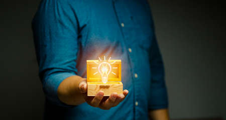man holding a wooden treasure box light bulb of wisdom uninterrupted thoughts brilliant conceptの写真素材