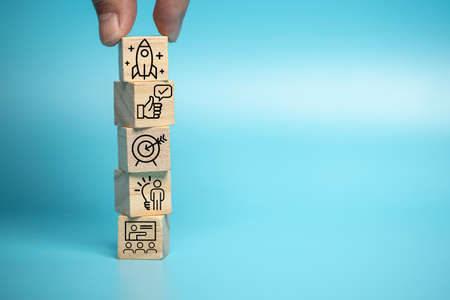 Businessman puts a wooden block of business symbols. Marketing and product planning ideas, startups,...