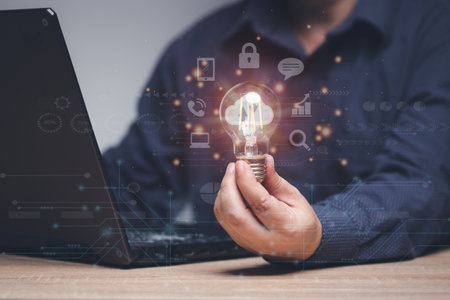 The concept of using technology in work. Man holding a light bulb that illuminates the idea of...