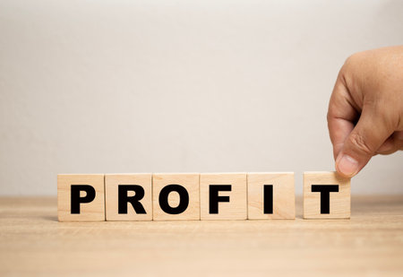 business profit concept. Businessman placing wooden block letter T per word to complete word profit. Planning and strategy for future profitability and growth of corporate company.の写真素材