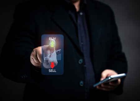 stock trading ideas concept. Businessman holding smart phone with stock graph showing various analytical data to make purchase decision. stock trading, forex, bitcoin, cryptocurrency.の写真素材