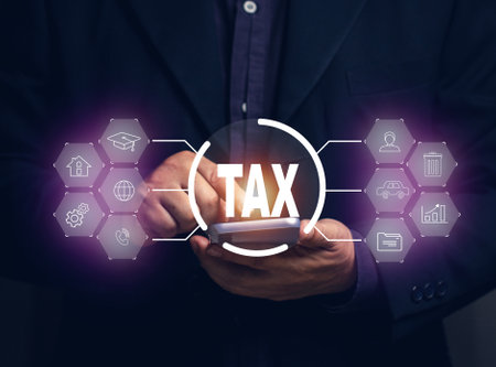 Online tax payment concept. Businessman paying taxes on mobile by filling out online utilities, medical bills, cars, homes, education, phone, stocks.の写真素材