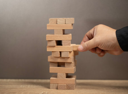 Planning, risk and strategy in business. man holds the model of business, made from wood blocks....