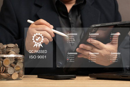 Quality Assurance in Financial Investments and Business Services. man reviewing quality control checklists on a tablet, ensuring service excellence and customer satisfaction. QC PASSED ISO 9001.の写真素材