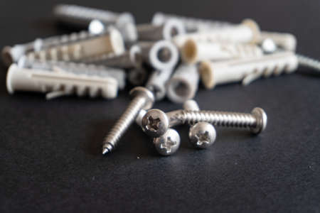 screws and wall plugs on a black background. Hardware concept