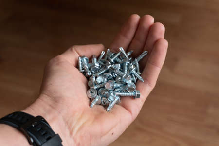 worker man hand holding a handful of screws