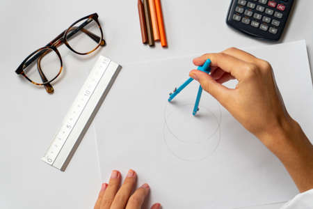 Drawing with a compass and a ruler on a blank sheet of paper. School concept