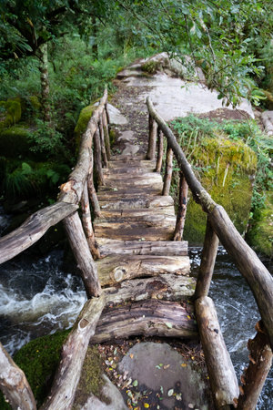 Old handmade wooden bridge over a river in Galicia. Water and nature conceptの写真素材