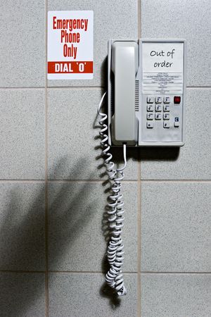 Shadow of hand reaching for out of order emergency phoneの写真素材