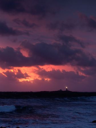 Lighthouse in stormy sunsetの写真素材