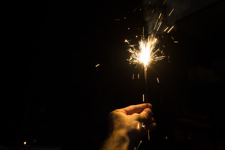 Hand holding a sparkler at nightの写真素材