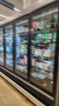A long row of glass-door freezers filled with boxed and bagged frozen meals and snacks in a modern...