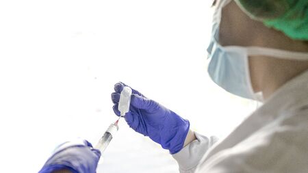 Midsection Of Female Nurse Holding Syringe Against White Background