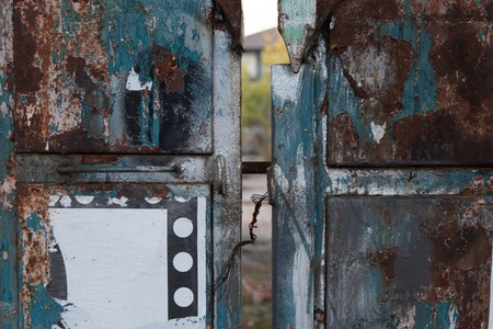 Old and rusty metal gate lock with traces of paint and damaged paperの写真素材