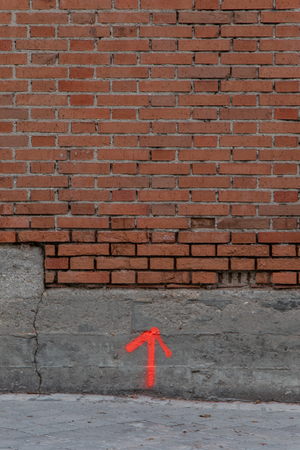 Red up arrow drawn on a wall with concrete and bricksの写真素材