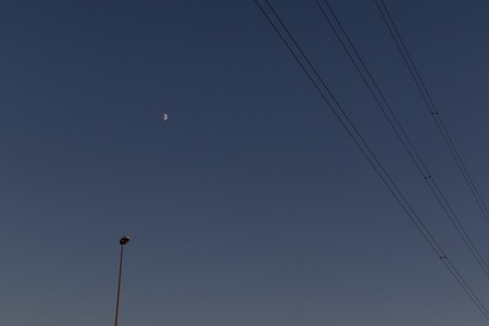 Telephone wires, street lamp and moon in the backgroundの写真素材