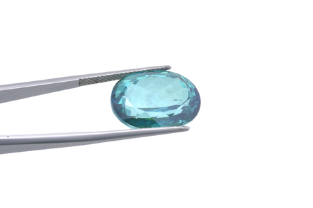 Macro photography of polished blue topaz gem fastened with jewelry tweezers on neutral backgroundの写真素材
