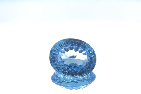 Macro image of a polished blue topaz gem on a reflective glass on neutral backgroundの写真素材