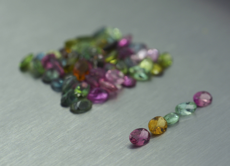 Group of precious stones of different colors and shapes on metal surfaceの写真素材