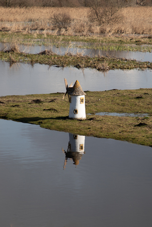 Whitewashed mill reflected in a lake on sunny dayの写真素材