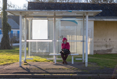 Girl waiting for the bus in a carport on sunny dayの写真素材