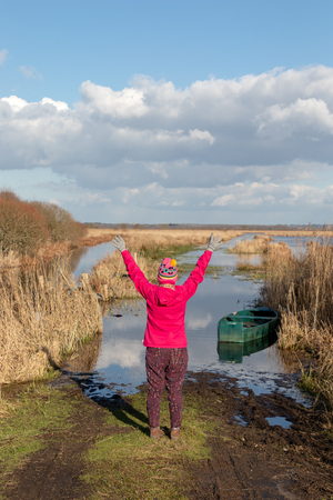 Girl raising her arms in front of a lake with a boatの写真素材