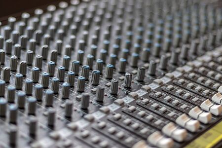 Mixing table with buttons and volume controls and red lights. Music and radio studioの写真素材