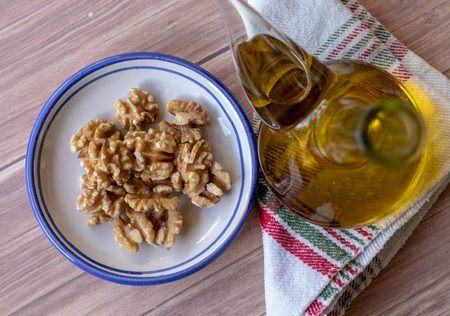 Healthy peeled nuts on a ceramic plate accompanied by a bottle of extra virgin olive oil. Top view with a rag..の写真素材