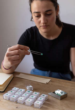 Young woman holding a precious stone with jewelry tweezers. Portrait of a gemologist.の写真素材
