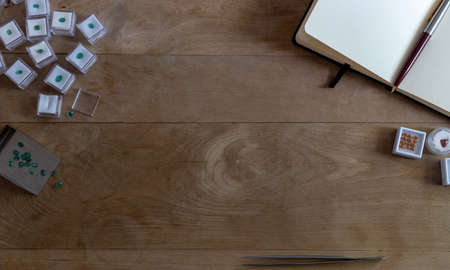 Wooden table with gems and jewelry tools like tweezers, shovel and blank open bookの写真素材