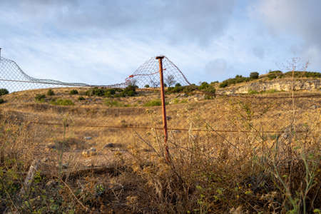 Metal fence in front of the dry field in late summer. Landscape of Castilla la Mancha, Spainの写真素材