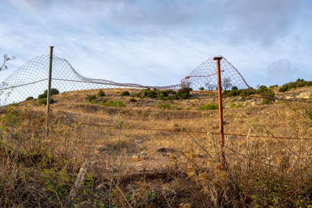 Metal fence in front of the dry field in late summer. Landscape of Castilla la Mancha, Spainの写真素材