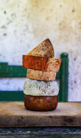 Different kinds of cheese. Assorted cheese tower on a wooden board in a rustic settingの写真素材