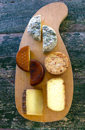 Top view of assorted cheeses on a rustic wooden board. Blue cheese, cured cheese, Manchego cheese, smoked cheese.の写真素材