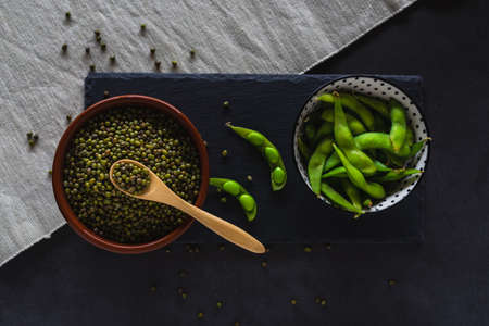 Bowls with mung beans and edamame pods. Green soybeans and healthy legumes.