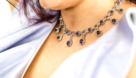Detail of luxurious and beautiful blue and silver sapphire pendant on the neck of a white womanの写真素材
