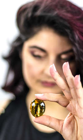 Beautiful woman holds a large yellow lemon quartz gemstone with sparkling facetsの写真素材